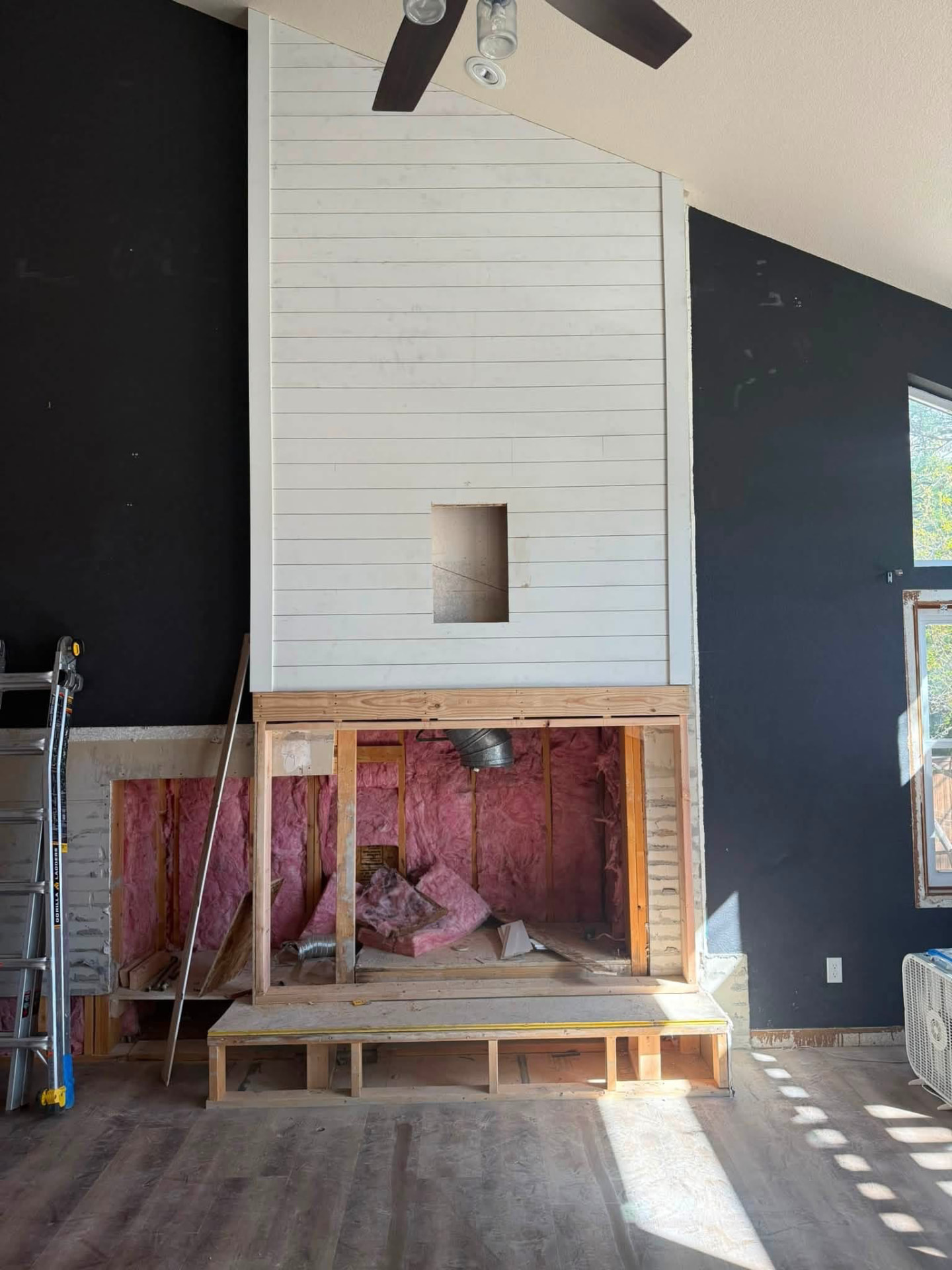 Fireplace remodel with white shiplap cladding above a framed hearth bench