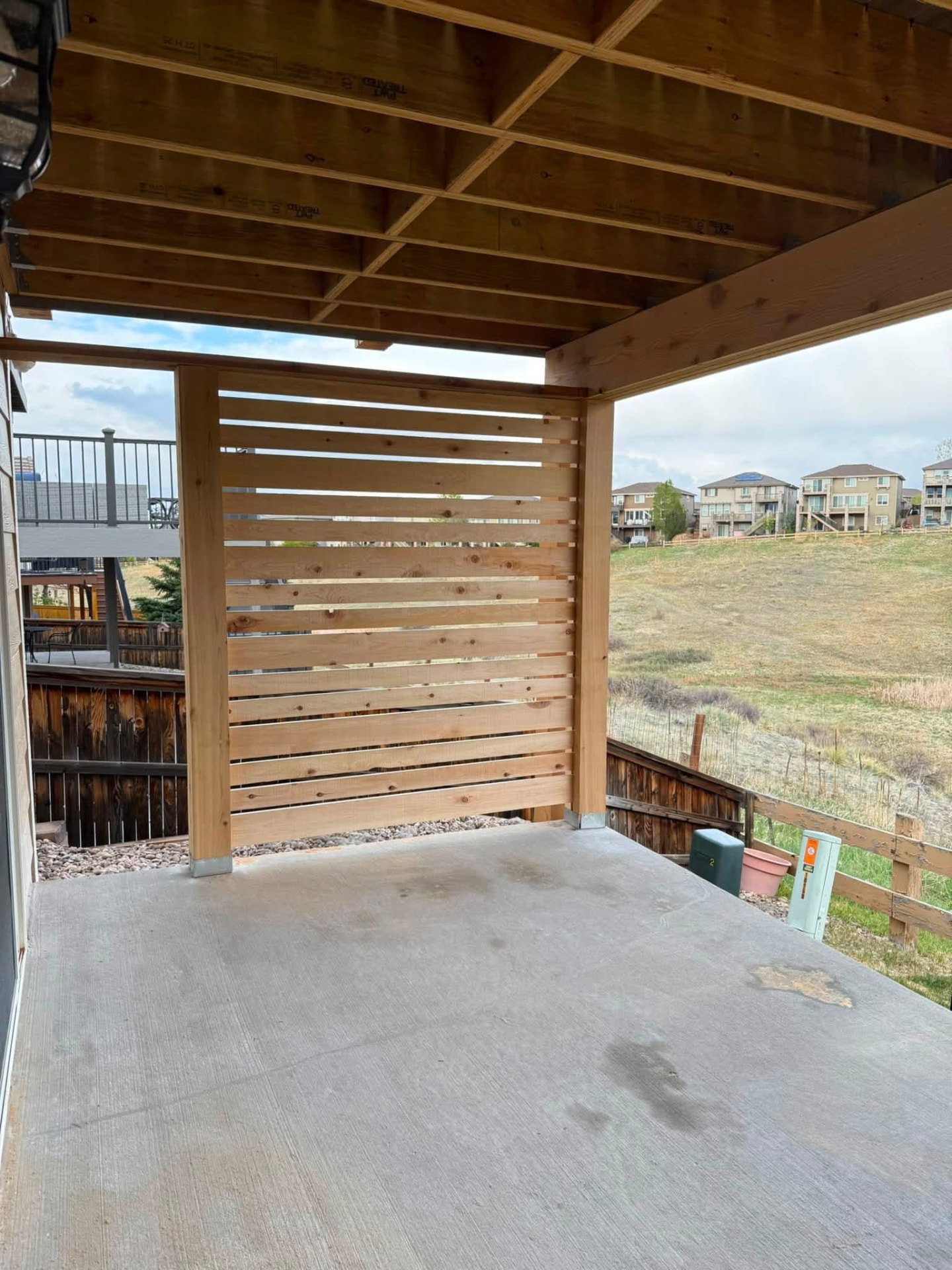 Horizontal wood privacy screen framed between timber posts beneath an upper deck