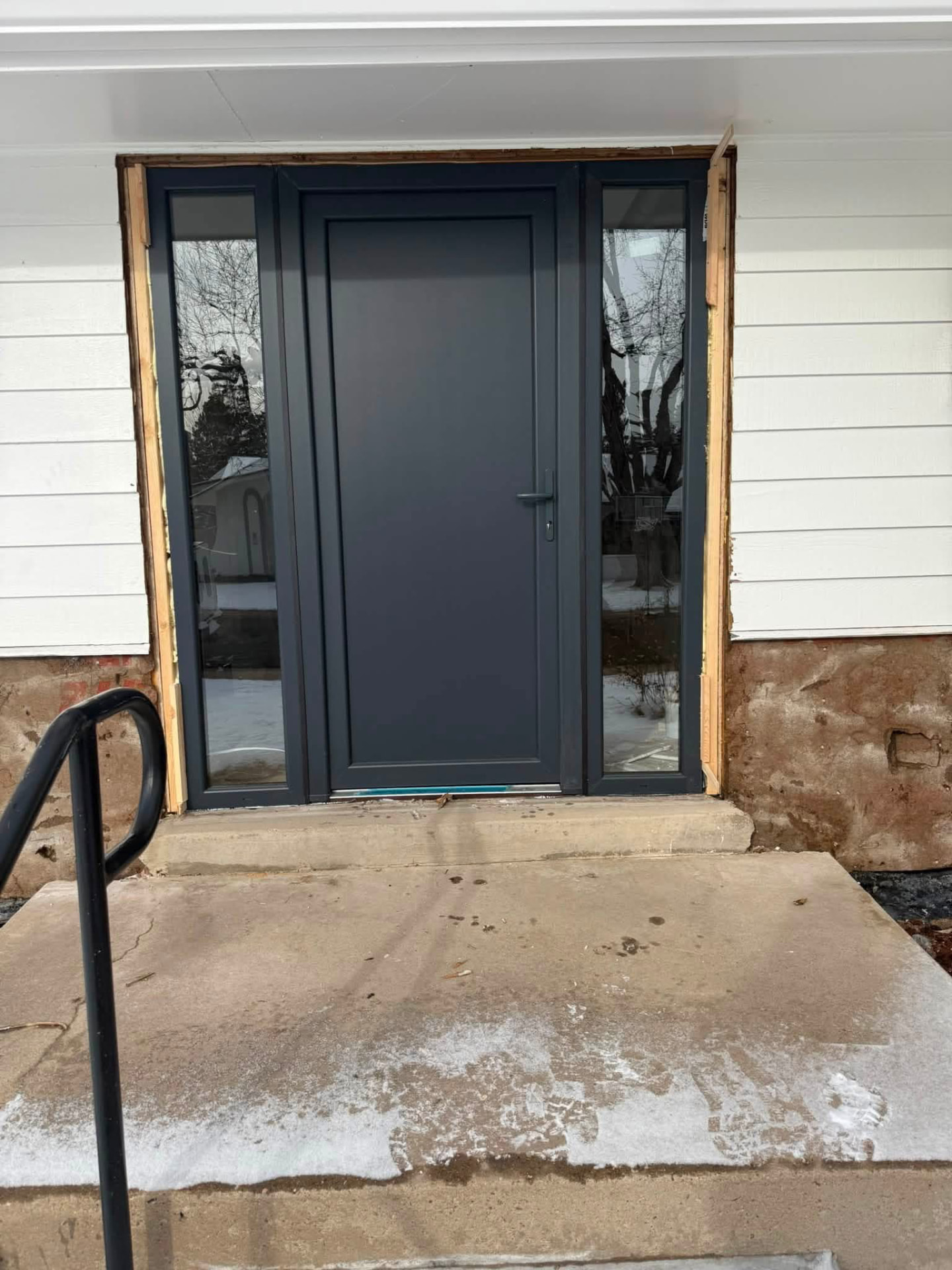 New dark gray entry door with sidelights during installation