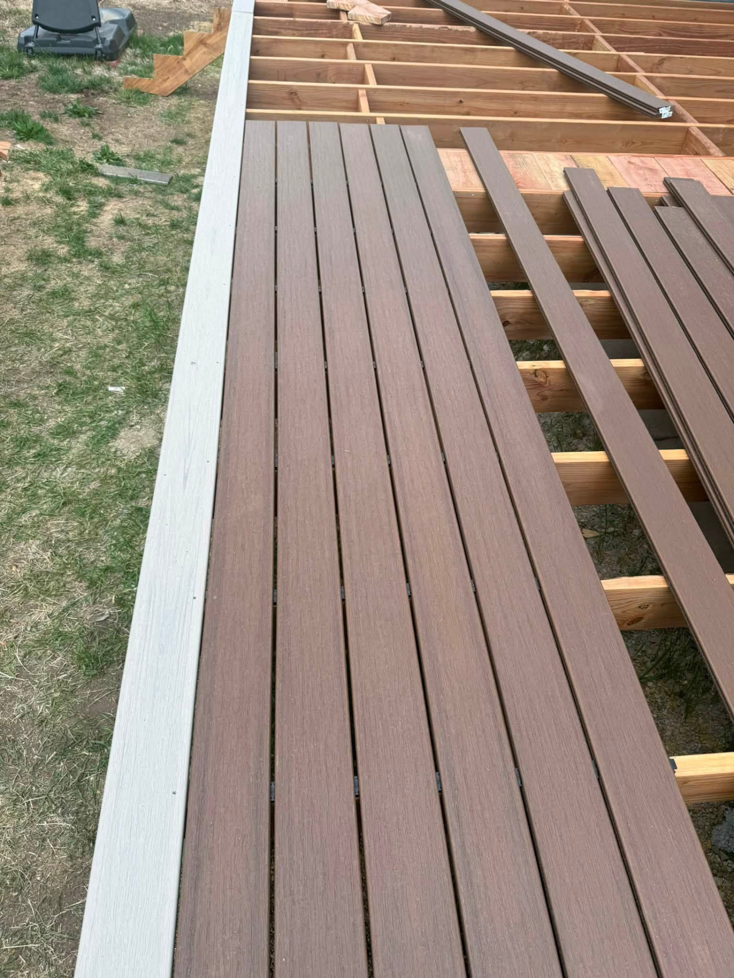 Composite deck boards being fastened over exposed framing