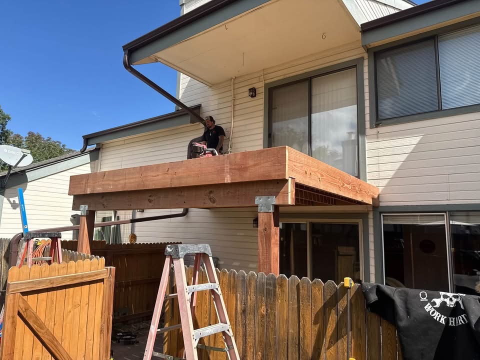 Residential deck construction in progress beside a two-story home