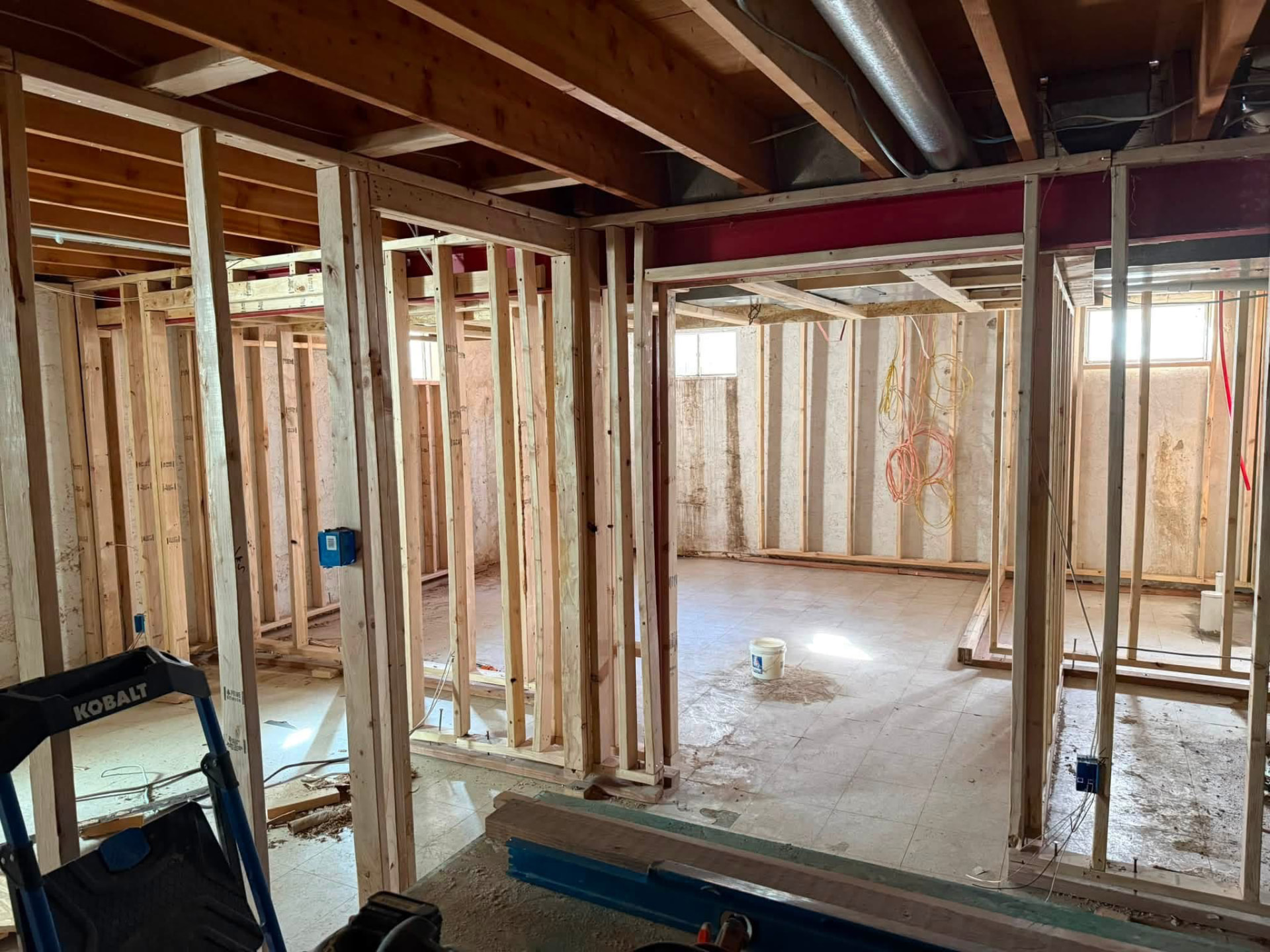 Basement room framing with rough electrical boxes and wire under exposed floor joists
