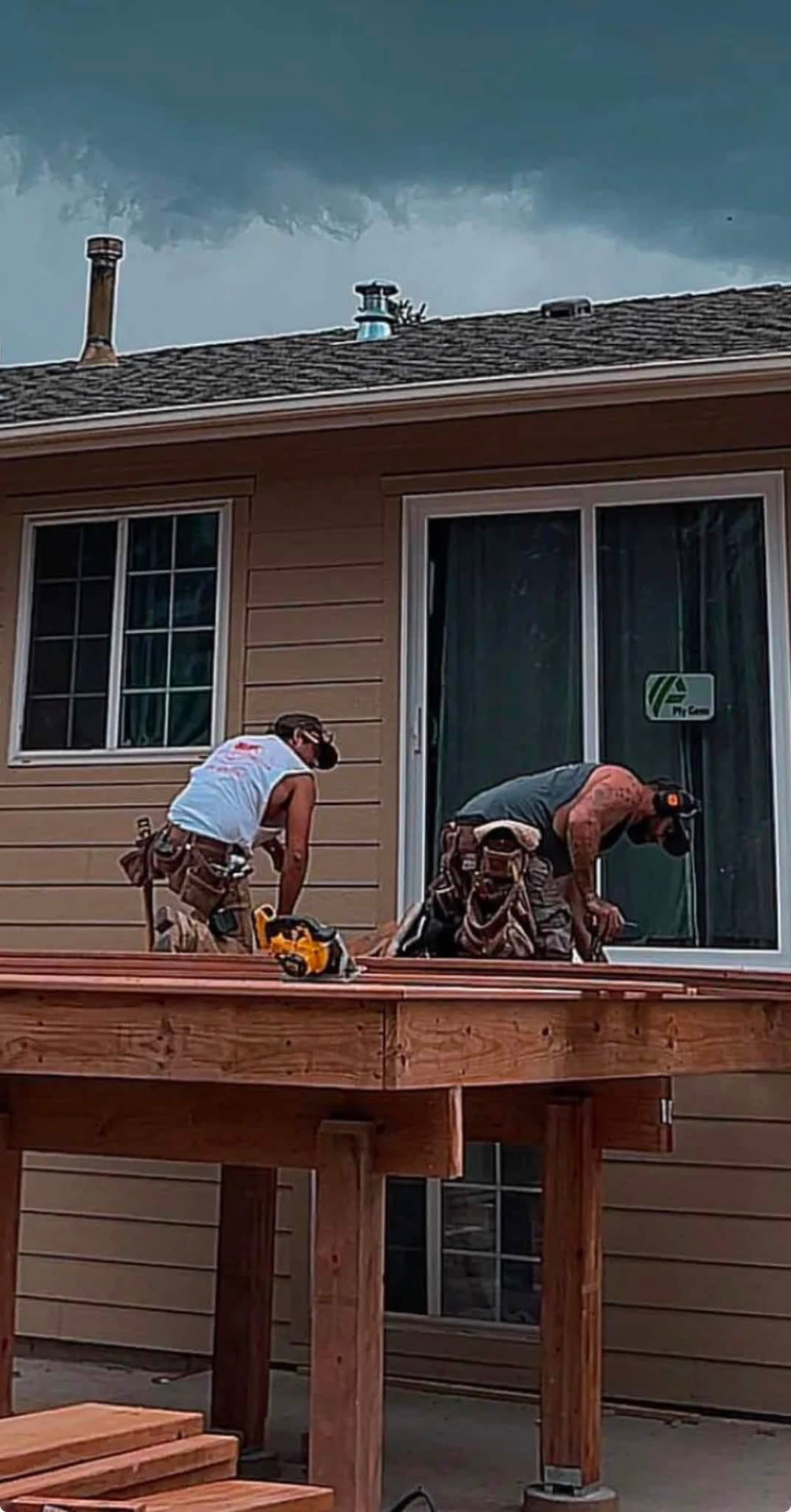 Carpenters framing an elevated deck beside a home