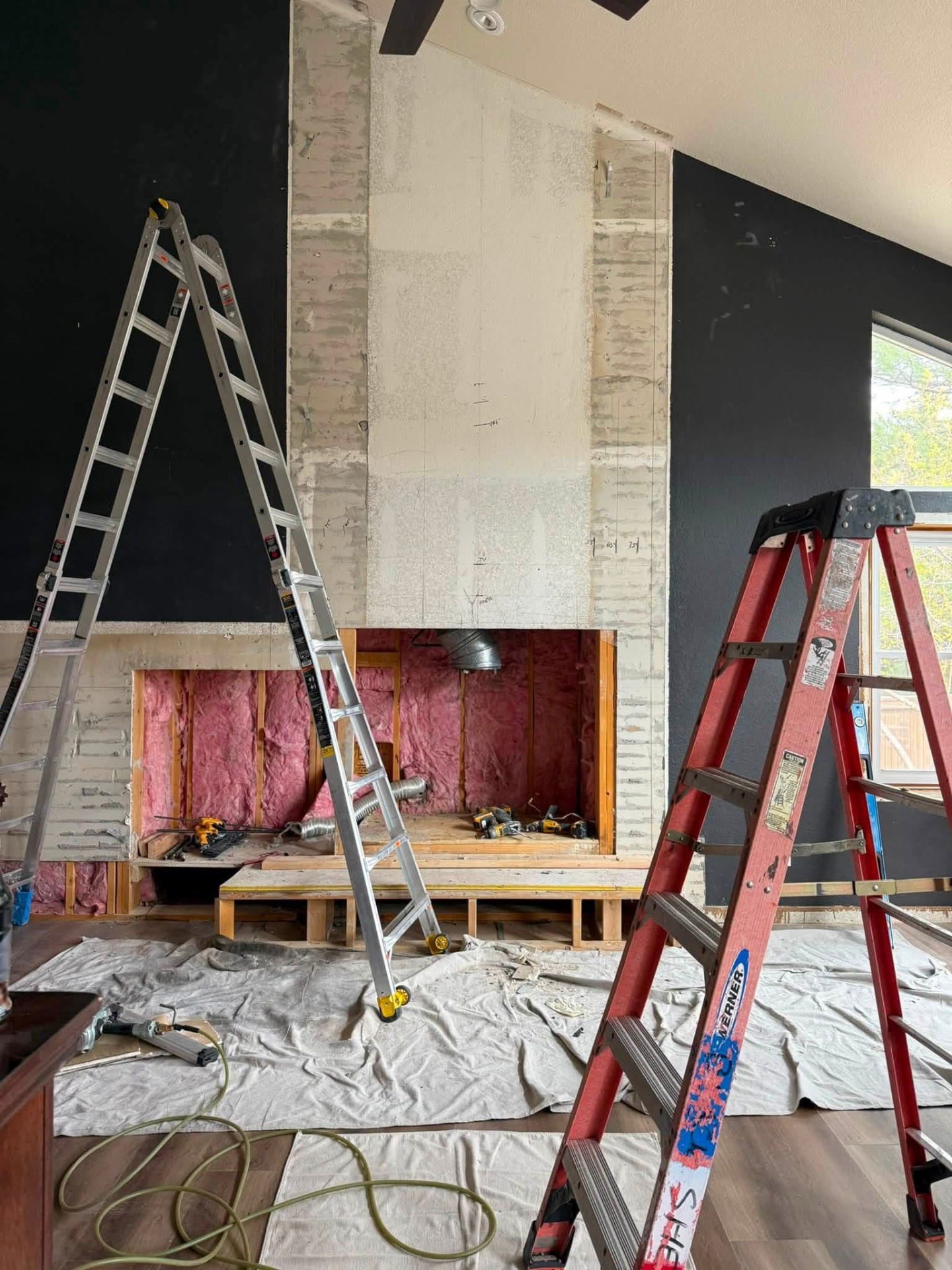 Fireplace wall stripped back to the substrate with the firebox framed out mid-remodel